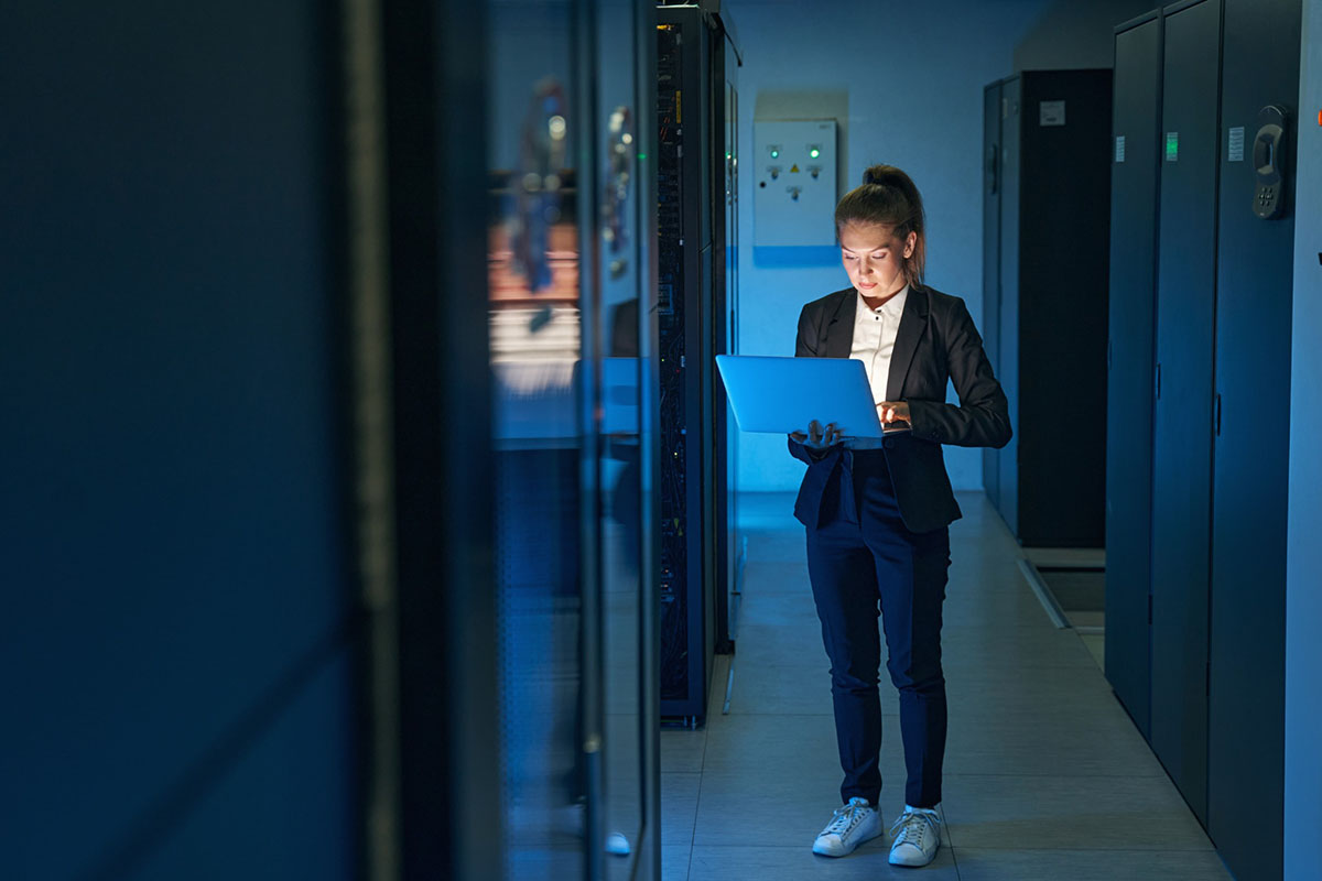 A technician using a laptop beside data centre equipment